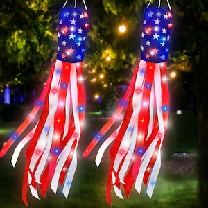 May include: Two cylindrical wind socks featuring a blue top section with white stars and long red, white, and blue fabric streamers. Each wind sock is illuminated with small, integrated LED lights that glow in red, white, and blue colors.