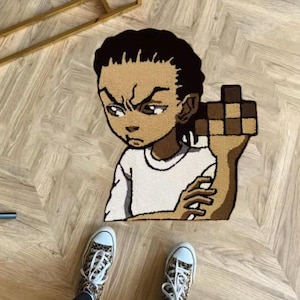 May include: A tufted rug featuring a cartoon character with a stern expression, holding a pixelated object. The rug is primarily beige, brown, and white, with a detailed design. The person is wearing leopard print sneakers.