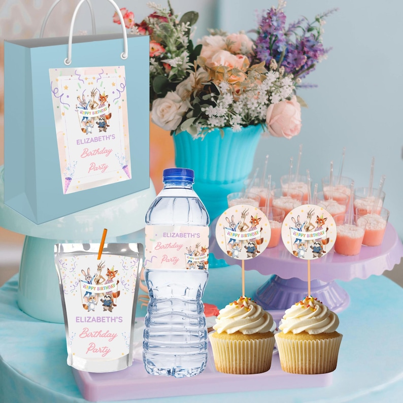May include: A light blue gift bag, water bottle, and drink pouch with matching labels that read "Elizabeth's Birthday Party." The labels feature cartoon animals. Cupcakes with white frosting and decorative toppers are also present.