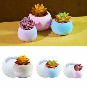 May include: Three round, white, ceramic succulent planters with different colored glazes. The planters are filled with artificial succulents in shades of green, pink, and yellow.