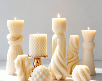 May include: A collection of ivory-colored, lit candles in various shapes. Designs include a knot, a cylinder with a bubble pattern, a spiral, and a figure-eight shape. Some candles are on a gold-colored stand.
