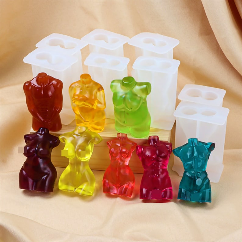 Op de afbeelding: Acht siliconen mallen voor het maken van harsfiguren. De mallen zijn wit en hebben elk twee holtes. De mallen zijn gevuld met kleurrijke harsfiguren in verschillende tinten rood, geel, groen, blauw en paars.