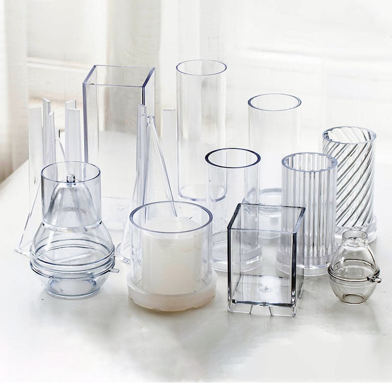 May include: A set of clear plastic candle molds in various shapes and sizes, including square, round, and cylindrical. The molds are perfect for making candles of different designs.