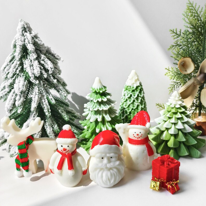May include: A set of Christmas-themed figurines, including a snowman, Santa Claus, a reindeer, and a gift box. The figurines are white with red and green accents and are surrounded by miniature green Christmas trees.
