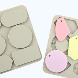 Può includere: Due stampi in silicone per la creazione di gioielli in resina. Lo stampo a sinistra ha sei forme diverse, tra cui un cerchio, un ovale, un rettangolo e una forma a cinque lati. Lo stampo a destra ha cinque forme diverse, tra cui un cerchio, un ovale, un rettangolo e due forme irregolari.