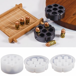 Puede incluir: Un juego de tres moldes de silicona transparentes para hacer dulces o jabón con forma de bala. Cada molde tiene ocho cavidades con forma de bala. Los moldes se muestran sobre un fondo blanco.