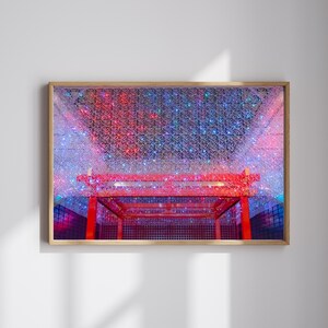 May include: A framed print featuring a red architectural structure with a grid-like design, set against a backdrop of a sparkling, colorful ceiling. The ceiling is illuminated with red, blue, and white lights, creating a vibrant and festive atmosphere.