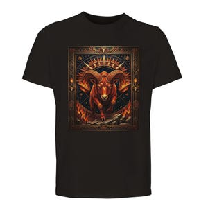 May include: Black t-shirt featuring a detailed illustration of a ram with fiery horns and a frame with sun and star designs. The ram is depicted in shades of red and orange, set against a dark blue background. The design is centered on the shirt.