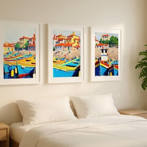 Può includere: Tre stampe artistiche incorniciate raffiguranti una scena costiera con barche ed edifici colorati. Le barche sono principalmente blu, gialle e rosse, con edifici con tetti arancioni. L'opera d'arte è esposta sopra un letto con biancheria da letto bianca.