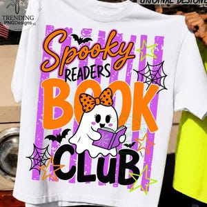May include: A white t-shirt featuring a graphic print with the text Spooky Readers Book Club. The design includes a white ghost wearing an orange polka dot bow, reading a purple book, surrounded by black bats, purple stripes, and neon stars.