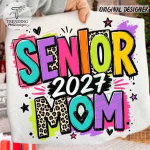 Puede incluir: Una camiseta blanca con un gr&aacute;fico colorido que muestra el texto SENIOR 2027 MOM. El dise&ntilde;o incluye letras brillantes en turquesa, morado, rosa, naranja, verde lima y amarillo, algunas con estampado de leopardo, acentuadas con estrellas negras.
