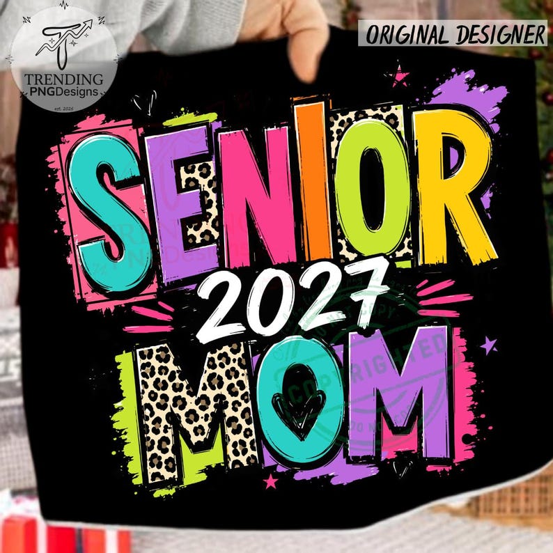 Puede incluir: Un dise&ntilde;o gr&aacute;fico negro con el texto SENIOR 2027 MOM en letras llamativas y coloridas. Las letras incorporan colores rosa brillante, turquesa, amarillo y verde lima con patrones de leopardo, salpicaduras de pintura y estrellas.