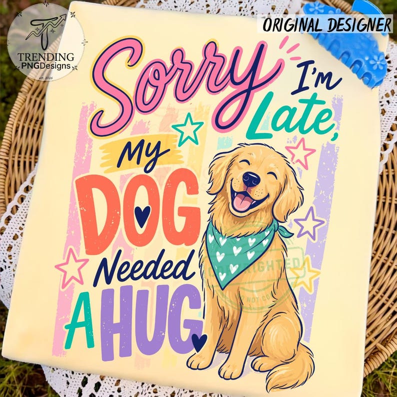 May include: A light yellow t-shirt featuring a golden retriever wearing a teal bandana with white hearts. The graphic includes the text Sorry I'm Late, MY DOG NEEDED A HUG in colorful, stylized lettering, accented by pink, teal, and purple stars.