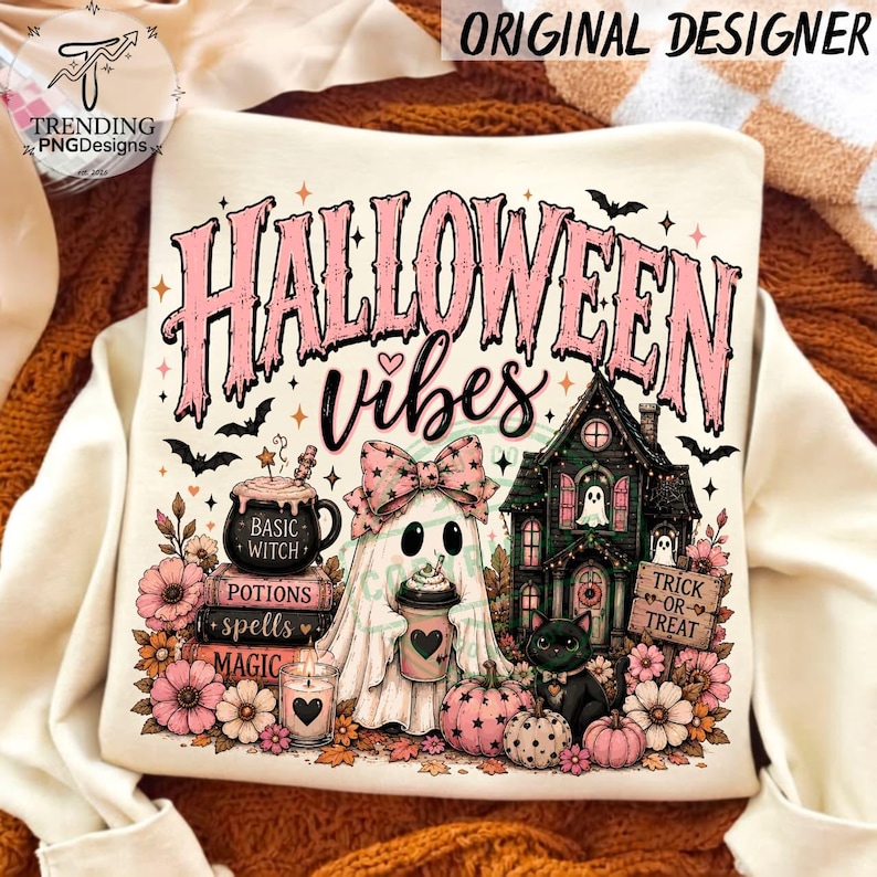 May include: A cream-colored sweatshirt featuring a graphic print with the text "HALLOWEEN vibes". The design includes a ghost with a pink bow holding a coffee cup, a black cat, a haunted house, a cauldron, books, pumpkins, and flowers.