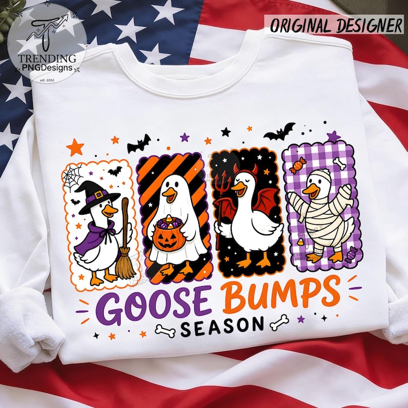 Op de afbeelding: Een wit sweatshirt met lange mouwen en een afbeelding van vier ganzen in Halloween-kostuums: een heks, een geest met een pompoen, een duivel en een mummie. De tekst "GOOSE BUMPS SEASON" staat in paars en oranje onder de ganzen gedrukt.