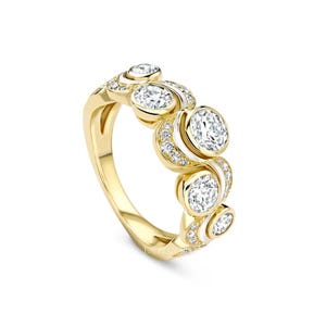 Puede incluir: Un anillo de oro con una serie de diamantes redondos engastados en bisel. Diamantes más pequeños están engastados a lo largo del diseño en espiral. El anillo tiene un acabado pulido y está sobre un fondo blanco.
