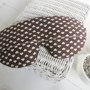 May include: A brown sleep mask with a pink heart pattern. The mask is made of soft fabric and is designed to block out light.