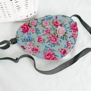 May include: A blue eye mask with a floral pattern. The mask has an adjustable elastic strap.