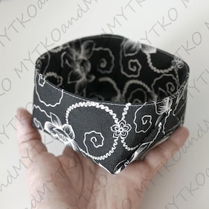Könnte beinhalten: Ein schwarz-weißer Stoffkorb mit Blumen- und Wirbelmuster. Der Korb wird in einer Hand gehalten und hat eine sechseckige Form. Innen und außen ist das gleiche Design zu sehen. Die Naht ist am oberen Rand sichtbar.