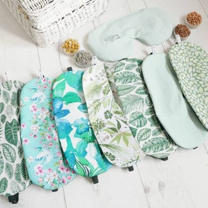 May include: A set of eight green and white eye masks with various leaf and floral patterns. The eye masks are made of soft fabric and are designed to block out light.