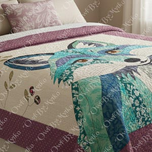 Puede incluir: Una colcha acolchada con un dise&ntilde;o de zorro en tonos azules, turquesas y grises. El dise&ntilde;o del zorro est&aacute; centrado en un fondo beige, con un borde morado oscuro. Tambi&eacute;n se ve una almohada a juego con un estampado floral.