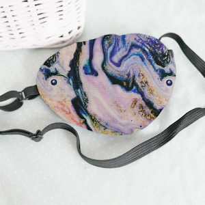 May include: A purple, blue and gold marble print eye mask with an adjustable black elastic strap.