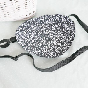 May include: A black eye patch with a white floral pattern and an adjustable elastic strap.