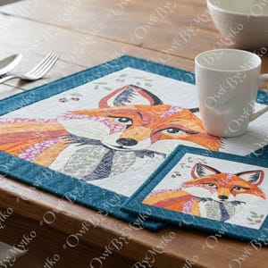 Puede incluir: Un juego de mantel individual y posavasos con un dise&ntilde;o de zorro en tonos naranja, blanco y gris, con un borde turquesa. Una taza blanca est&aacute; sobre el mantel individual. El conjunto est&aacute; sobre una mesa de madera.