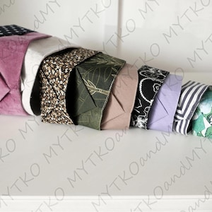 May include: An assortment of folded fabric pieces in diverse patterns and colours, such as navy with white stars, mauve, floral, and striped designs. The items are arranged in a cascading, layered display.