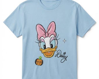 May include: A light blue short-sleeve t-shirt featuring an embroidered graphic of Daisy Duck with a pink bow, a small orange pumpkin, and the script text Daisy. The design includes a small four-pointed star accent to the right of the character.