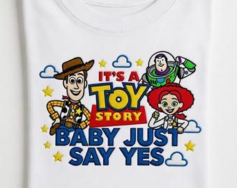 May include: A white t-shirt featuring a colorful graphic of Woody, Buzz Lightyear, and Jessie from Toy Story. The design includes the text IT'S A TOY STORY BABY JUST SAY YES in blue and red, surrounded by yellow stars and blue cloud outlines.