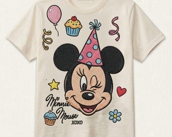 May include: A cream-colored short-sleeve t-shirt featuring an embroidered graphic of Minnie Mouse wearing a pink polka-dot party hat. The design includes a balloon, cupcakes, streamers, a star, a heart, a flower, and the text Minnie Mouse XOXO.