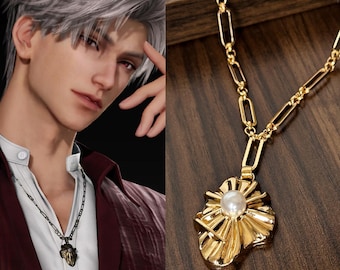 Puede incluir: Collar dorado con un colgante con una perla central y un diseño de rayos de sol. El collar tiene una cadena delicada con eslabones rectangulares. El colgante está sobre una superficie de madera.