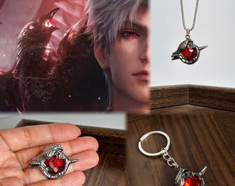May include: A silver-toned metal pendant necklace and a matching keychain, both featuring a stylized bird design with a faceted, deep red gemstone at the center. The bird motif has intricate wing detailing and a sharp, pointed beak, reflecting a dark aesthetic.