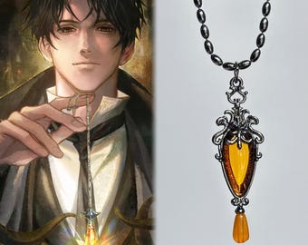Puede incluir: Un collar de tono plateado con un colgante alargado en forma de lágrima de color ámbar, encerrado en un marco de metal filigranado. El colgante incluye una cuenta más pequeña de color ámbar que cuelga en la base y una cadena plateada.