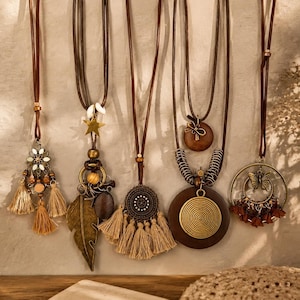 May include: A selection of bohemian necklaces with brown leather cords. The pendants showcase diverse designs, including tassels, a star, a leaf, a spiral, and a butterfly. The color scheme incorporates brown, gold, and beige.