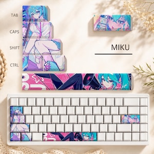 May include: A mechanical keyboard with white keys and a set of custom keycaps featuring anime-style illustrations of a character with teal hair. The keycaps display the text MIKU, TAB, CAPS, SHIFT, and CTRL, with vibrant pink and blue color schemes.