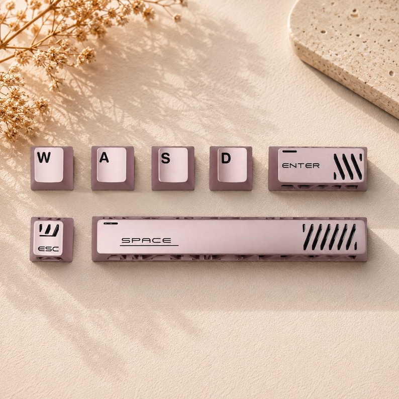 May include: A set of mauve and white mechanical keyboard keycaps including W, A, S, D, ESC, ENTER, and SPACE keys. The keys feature black lettering and decorative diagonal slit patterns on the ENTER and SPACE bars, with a textured base design.