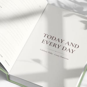 May include: Open journal with lined pages and the text "TODAY AND EVERY DAY". The journal has a light green spine and a light-colored cover. The text "Celebrate Today - Create Tomorrow" is below the main text.