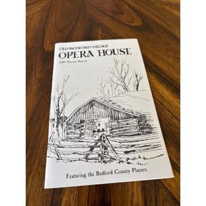 May include: A vintage program for the Old Bedford Village Opera House, featuring a detailed pen and ink illustration of a rustic building. The cover includes the text "1989 Theatre Season" and "Featuring the Bedford County Players."