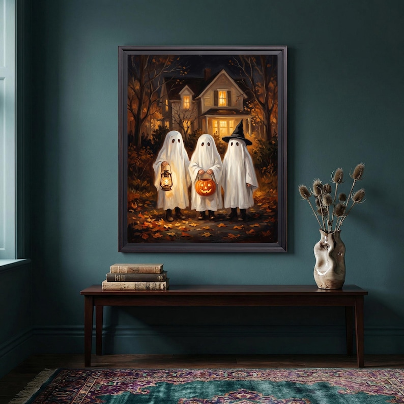 Puede incluir: Una impresi&oacute;n art&iacute;stica enmarcada que representa a tres figuras vestidas con disfraces de fantasmas blancos frente a una casa por la noche. Un fantasma sostiene una linterna encendida, otro lleva una calabaza y el tercero lleva un sombrero de bruja negro.