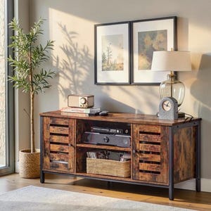 May include: A rectangular media console with a rustic brown wood-grain finish and a black metal frame. It features two slatted cabinet doors, an open centre shelf containing electronic devices, and a woven basket for storage on the bottom shelf.