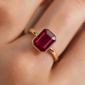Anello di fidanzamento con rubino taglio smeraldo e solitario incastonato in oro 14 carati.