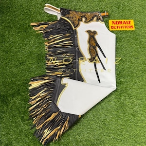 May include: White and black leather chaps with gold fringe and decorative stitching. The chaps have a white front panel with a gold embroidered design. The text "NORAIS OUTFITTERS" is visible on a yellow rectangle.