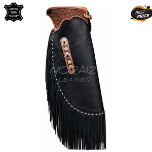 May include: Black leather chaps featuring a tan leather waistband with a textured pattern, long black fringe along the side, and a vertical row of silver-toned decorative conchos. The text NORAIZ LEATHER is visible on the surface of the chaps.