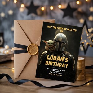 May include: A birthday invitation featuring a Star Wars theme. The invitation card has the text "MAY THE FORCE BE WITH YOU ON LOGAN'S BIRTHDAY" in gold lettering. An envelope with a black ribbon and a gold wax seal is next to the invitation.