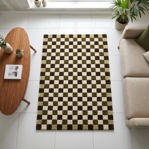 Op de afbeelding: Een rechthoekig vloerkleed met een dambordpatroon in bruin, groen en cr&egrave;me. Het kleed ligt op een witte tegelvloer, met een houten salontafel en een beige bank op de achtergrond. Het kleed voegt een geometrisch designelement toe aan de kamer.