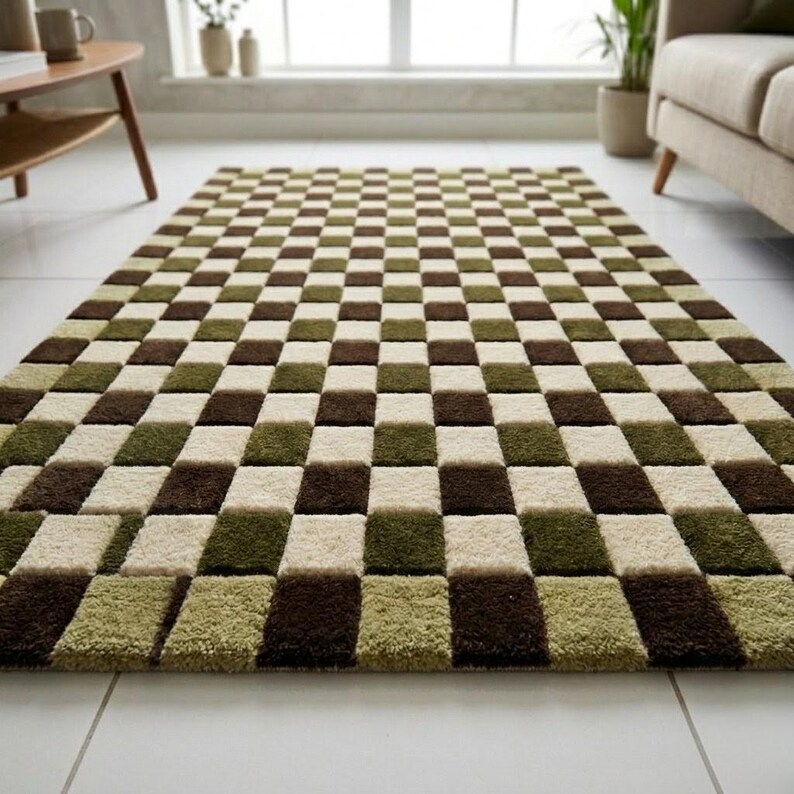 Op de afbeelding: Een rechthoekig vloerkleed met een dambordpatroon. Het kleed heeft afwisselende vierkanten in bruin, olijfgroen en cr&egrave;me. Het kleed is gemaakt van een zacht, pluche materiaal en ligt op een witte tegelvloer.