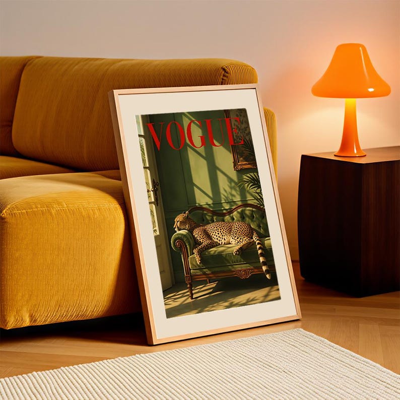 May include: A framed wall art print featuring a vintage-style magazine cover with the word VOGUE in red letters. The image depicts a leopard resting on a green velvet sofa inside a room with sunlight casting shadows through a window frame.