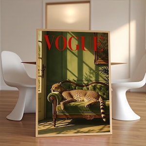 May include: A rectangular wall art print featuring a cheetah resting on a green tufted sofa inside a room with green walls and a doorway. The word VOGUE is printed in large red capital letters at the top of the image, which is framed in light wood.